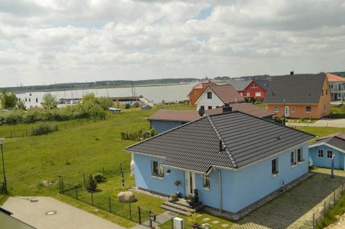 a blue house with a black roof in a field at FH Das blaue Haus am Peenestrom in Peenemünde