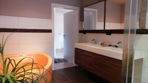 ein Badezimmer mit einer orangen Badewanne und einem Waschbecken in der Unterkunft Villa Moma in Bad Harzburg