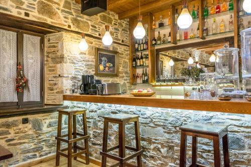 un bar con dos taburetes en una pared de piedra en Iliopetra Suites en Agios Lavredios