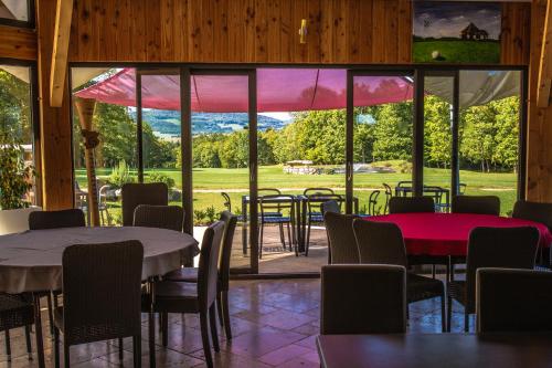 a room with tables and chairs and a large window at Golf de La Chassagne in Mâlain