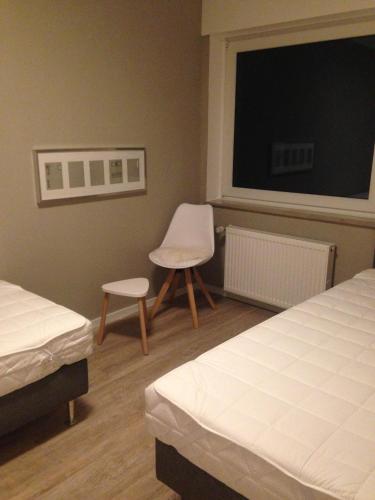 a bedroom with two beds and a chair and a window at Beverlodge in Telgte