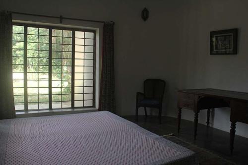 a bedroom with a bed and a desk and a window at Isai Ambalam guest house in Puducherry