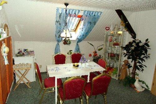 a dining room with a white table and red chairs at Pension Renate Braun in Gamstädt