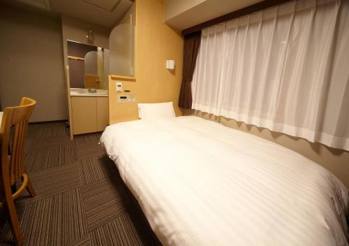 a bedroom with a large white bed with a window at Dormy Inn Hiroshima in Hiroshima