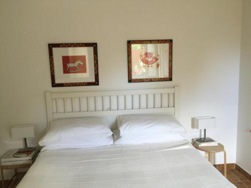 um quarto com uma cama branca e duas fotografias na parede em FdM Stay 1 em Forte dei Marmi