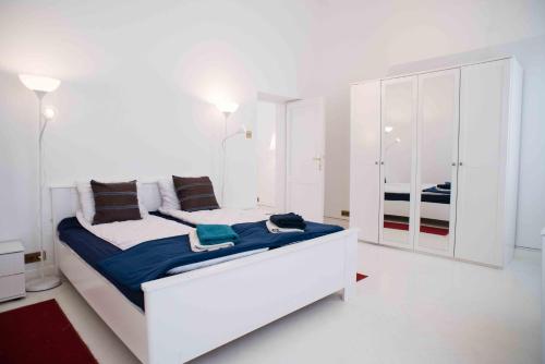ein weißes Schlafzimmer mit einem großen Bett mit blauer Bettwäsche in der Unterkunft Splendid Trees Apartment in Budapest