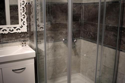 a shower with a glass door next to a sink at Pera City Hotel in Ankara