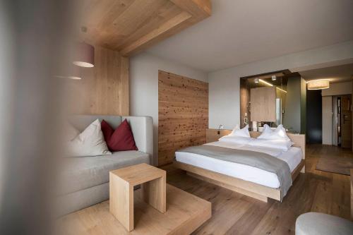 een slaapkamer met een bed en een bank bij Das Panorama Designhotel in Caldaro