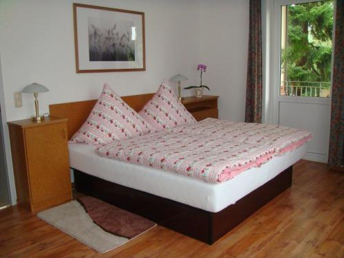 a bedroom with a bed with pink pillows and a window at Ferienwohnungen Rosengarten in Bad Elster