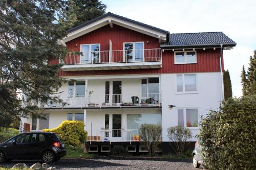 a red and white house with a car parked in front at Ferienwohnung in Marburg/Wehrda in Marburg an der Lahn