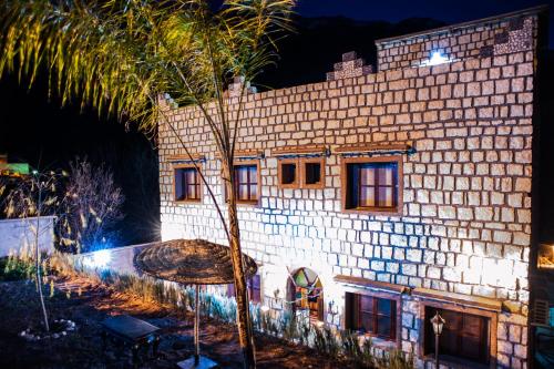 a large brick building with a palm tree in front of it at Toubkal Ecolodge in Imlil