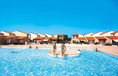 two women standing in a swimming pool at a resort at Barcaresa-Villa Vue Mer Accès Direct Plage - Piscine in Le Barcarès