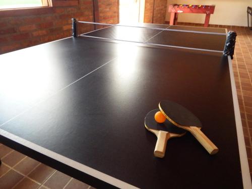 a ping pong table with a racket and an orange on it at Pousada Chalés da Felicidade in Itu