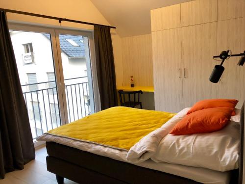 a bedroom with a bed with yellow sheets and orange pillows at Ski Sun Sea - Rodzinny apartament pod gondolą in Świeradów-Zdrój