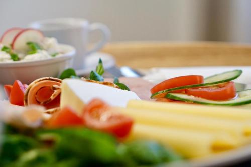a plate of food with cheese and vegetables on a table at Apartament White in Śrem