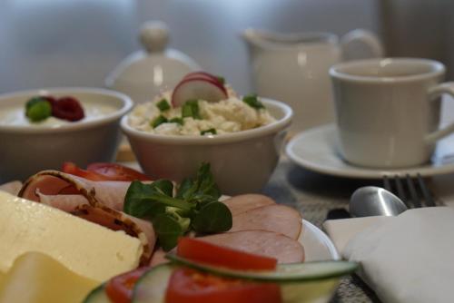 a table with a plate of food and bowls of food at Apartament White in Śrem