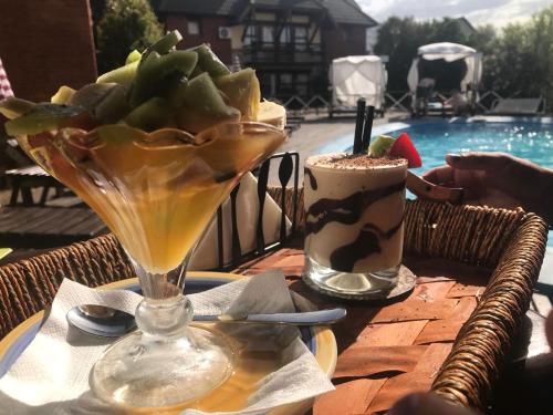 una mesa con un martini y una copa junto a una piscina en el Hotel y Spa Arenarena de Villa Gesell