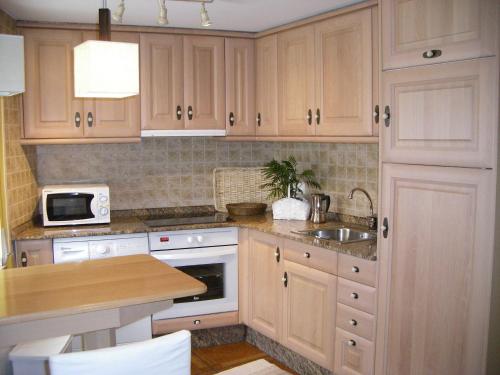 una cocina con armarios de madera y fregadero en Apartamento Sopiedra, en Nueva de Llanes