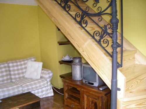 a living room with a staircase with a tv and a couch at Apartamento Sopiedra in Nueva de Llanes