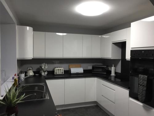 a kitchen with white cabinets and a black counter top at Number 13 in Lerwick
