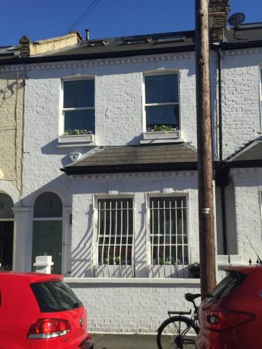 a white brick house with two windows and a bike parked in front at Fulham B&B in London