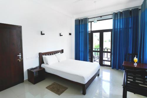 a bedroom with a bed and a desk and a window at Kaminrich Cottage in Matara