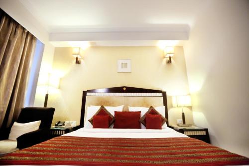 a hotel room with a large bed with red pillows at Venizia Sarovar Portico in New Delhi