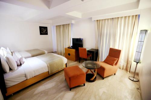 a hotel room with a bed and a desk and chair at Venizia Sarovar Portico in New Delhi