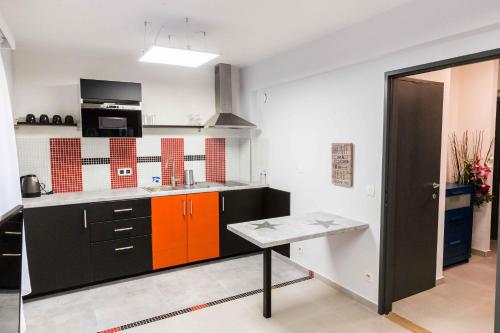 una cucina con armadi arancioni e neri e un tavolo di Apartment in Antwerp city centre ad Anversa