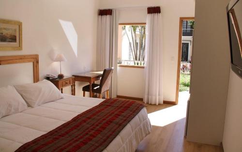 a bedroom with a bed and a desk and a table at Hotel Casablanca Koeler in Petrópolis