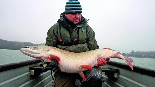 a man holding a fish in front of a boat at The Pytchley Inn in West Haddon
