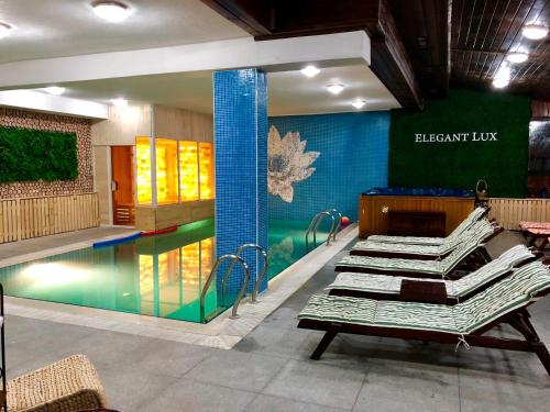a room with a swimming pool with chairs and a table at Elegant Lux Hotel in Bansko