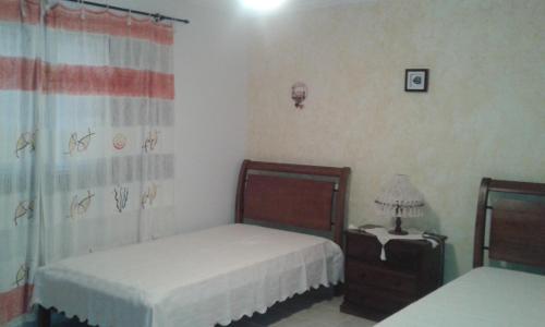 a bedroom with two beds and a table with a lamp at Casa de praia Peruibe in Peruíbe