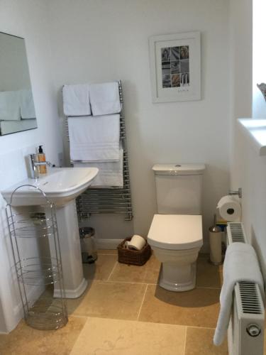 a bathroom with a sink and a toilet and towels at Little Owl Barn in Marlborough