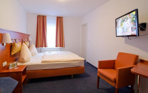 a hotel room with a bed and a chair at Hotel -Restaurant Taormina in Birkenfeld