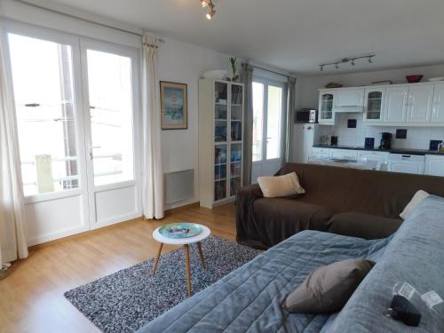 een woonkamer met een bank en een tafel bij Le clapotis de l'Ô, calme, balcon sur la mer, à 2 h de Paris in Ault
