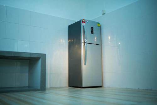 a refrigerator in a room with a wall at SingVillage Holiday House in Mersing
