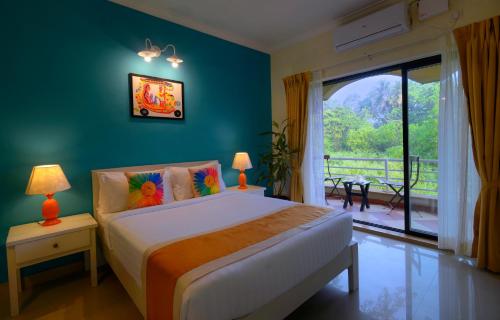 a bedroom with a bed and a large window at TreeHouse Blue Hotel & Villas in Colva