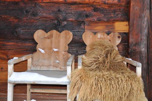une chaise en bois avec du foin assis devant un mur dans l'établissement Telemark Guesthouse, à Nendaz