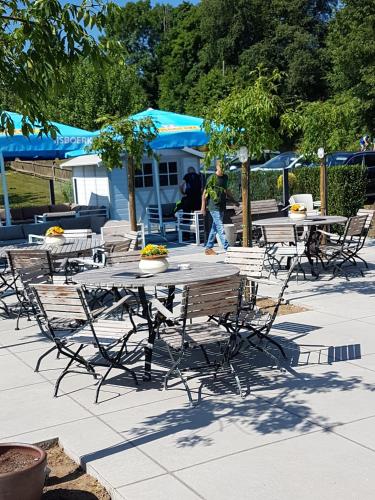 a group of tables and chairs with a man walking by at De Hollemeersch Hotel in Dranouter