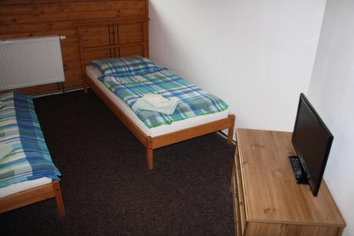 a room with two beds and a table with a tv at Penzion u Hajneho Bedricha in Harrachov