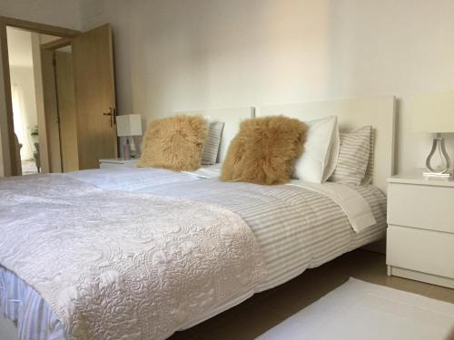 um quarto com uma cama branca e 2 almofadas peludas em SolTroia Glamorous Apartament em Troia