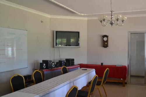 a meeting room with a table and chairs and a white wall at Honeybed Lodge in Lusaka