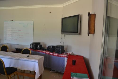 a room with two tables and a tv on the wall at Honeybed Lodge in Lusaka