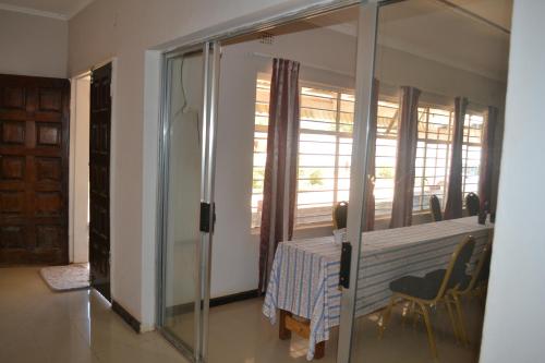 a dining room with a table and a glass door at Honeybed Lodge in Lusaka