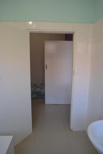 a bathroom with a white door and a sink at Honeybed Lodge in Lusaka