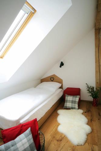 a bedroom with a white bed and a red chair at Apartments and Rooms Kaja in Kranjska Gora