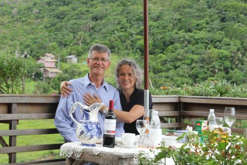 un hombre y una mujer sentados en una mesa con botellas de vino en Casa na montanha com vista para o mar, en Florianópolis