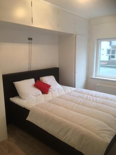 a bedroom with a white bed with two red pillows at appartement zeedijk westende in Middelkerke