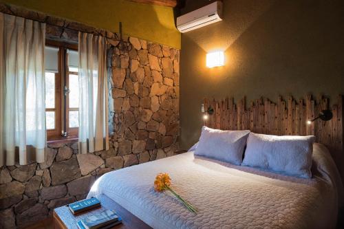 a bedroom with a large bed with a stone wall at Puesto Victoria - Adults only in Yacanto